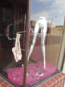 Ballet slippers and sterling, disembodied legs in a shop window.